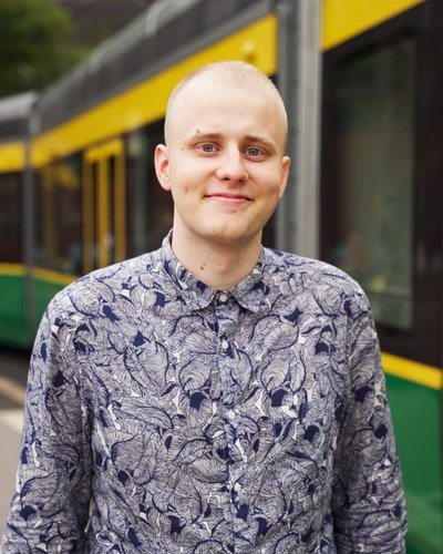 Akseli hymyilee, taustalla helsinkiläinen raitiovaunu